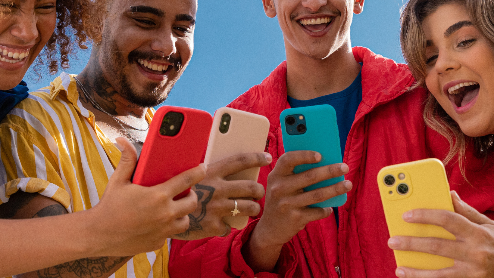 4 friends looking at their phones together.
