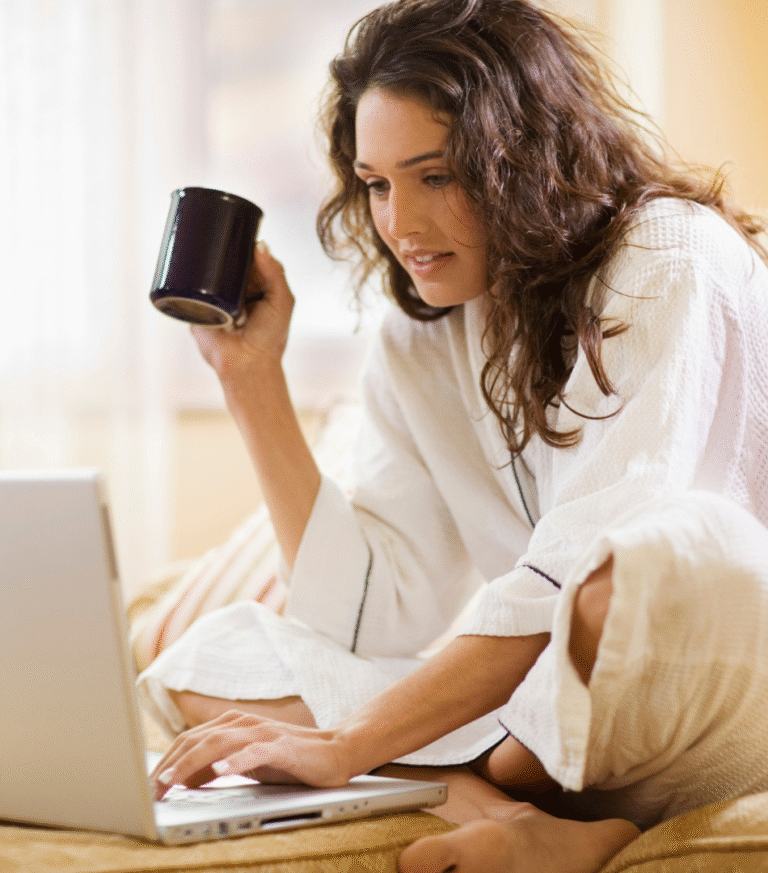 Smiling business owner working at a laptop with a notebook and cup of tea, feeling calm and clear about her content strategy